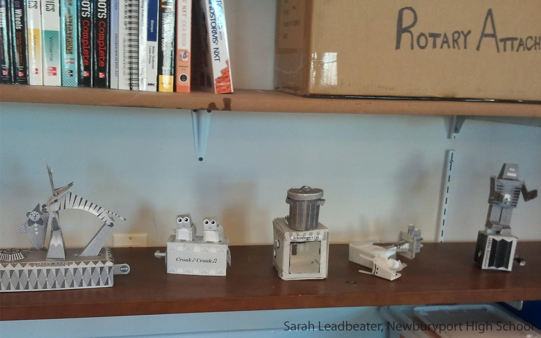 Shelf with books above and robot figurines below, including a crook-shaped robot and metal machines.