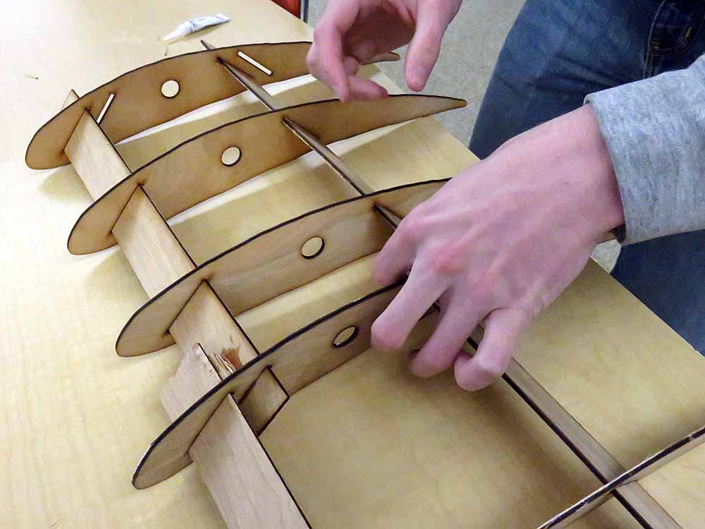 Hands assembling wooden toy fish puzzle pieces with tabs and slots
