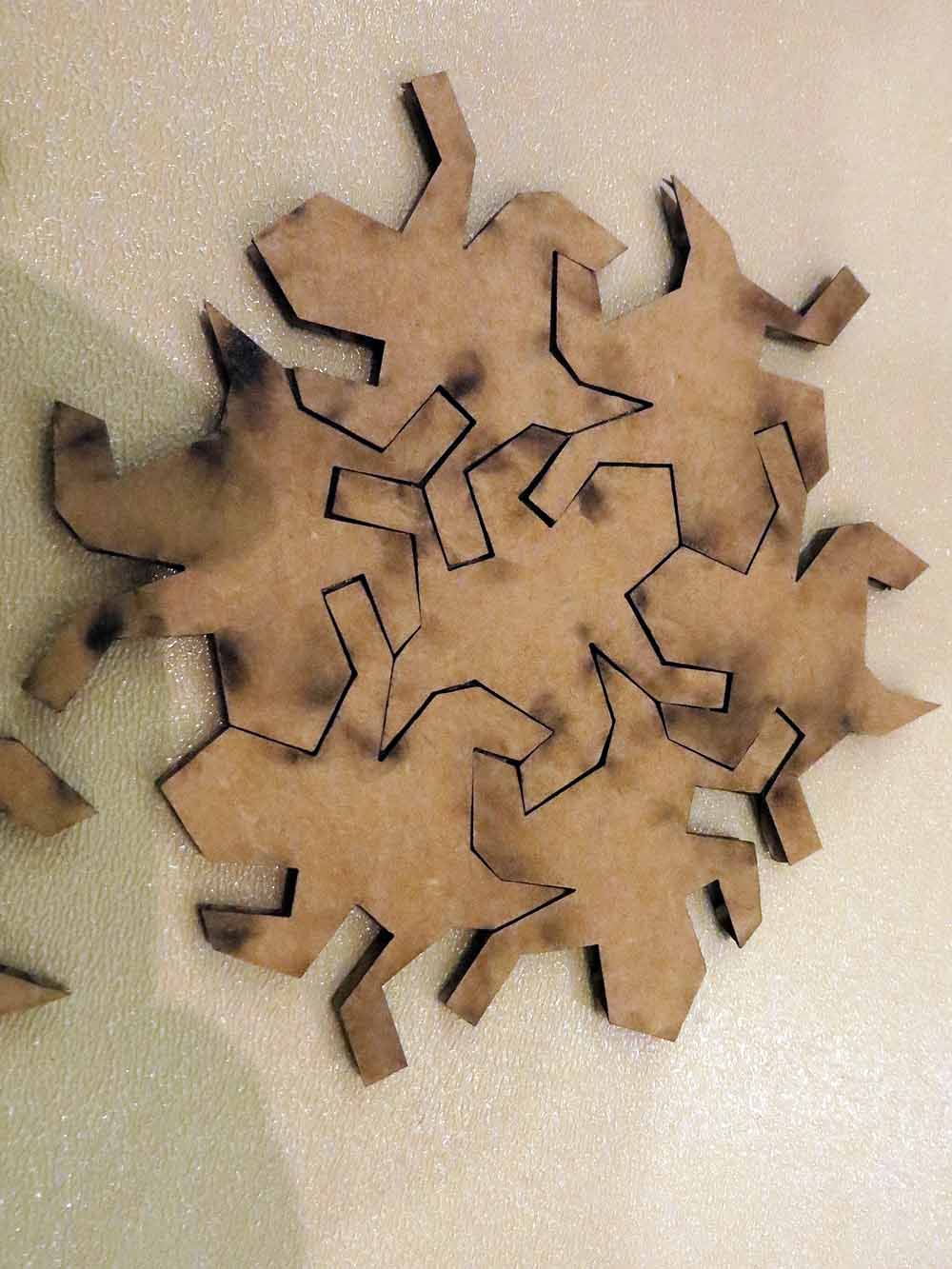 Brown cardboard puzzle with interlocking pieces mounted on a textured wall