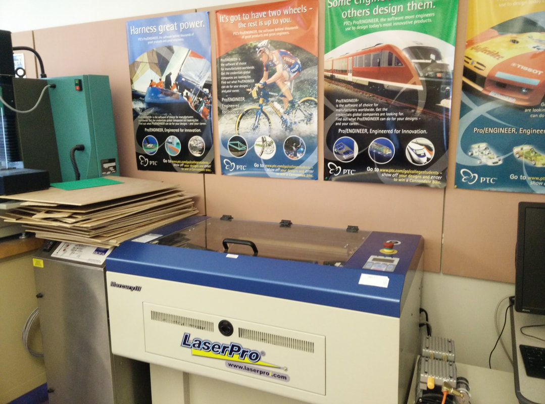 LaserPro machine in engineering office with ProEngineer promotional posters on wall