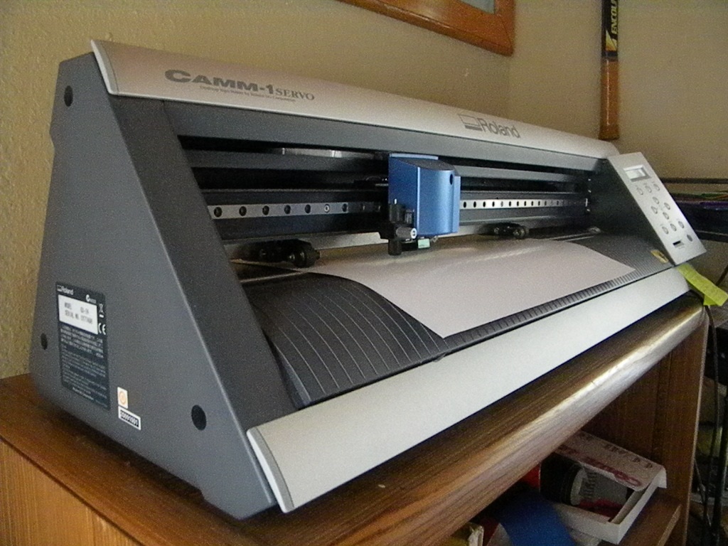 CAMM-1 Servo cutting plotter machine on wooden desk with paper and blue cartridge