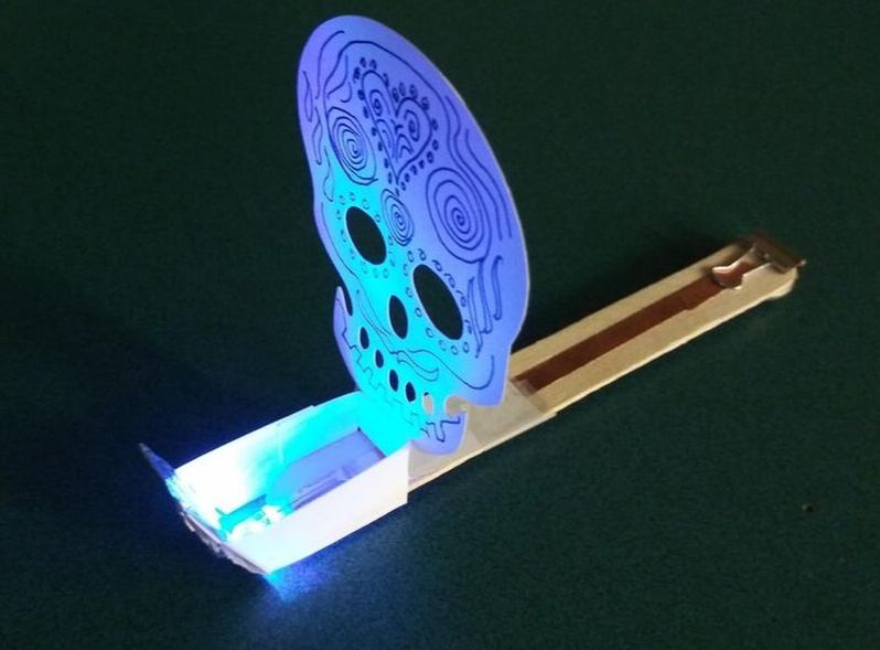 Glowing blue skull-shaped decoration with intricate patterns on wooden stick