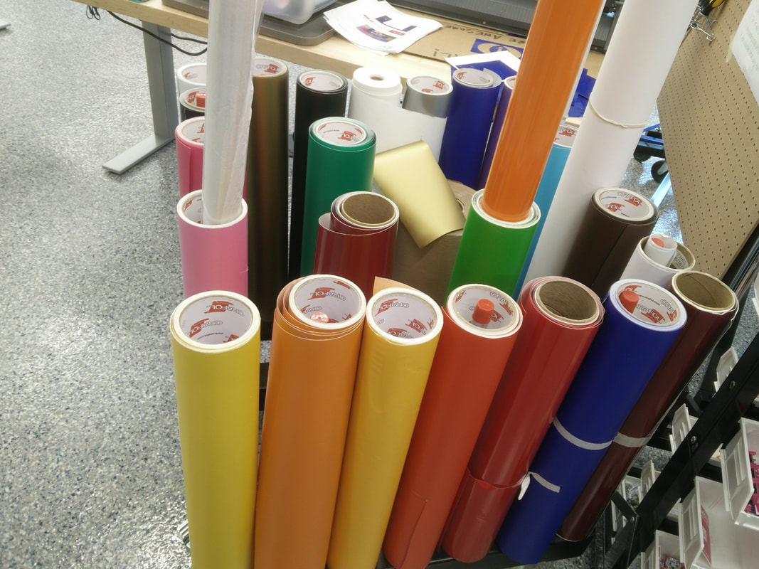 Vinyl rolls stored vertically on a shop-made rack - note the pipe ends visible in the center of the rolls.