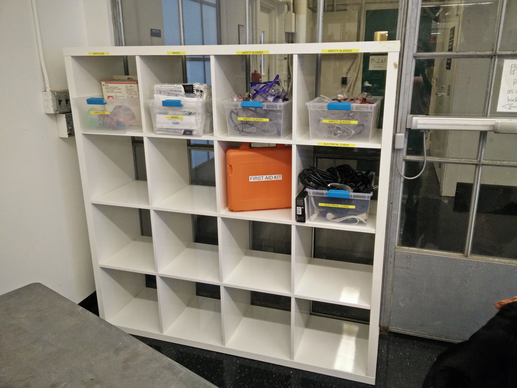In this Makerspace, the first aid kit is stored appropriately with other safety gear like glasses, gloves, and ear protection.