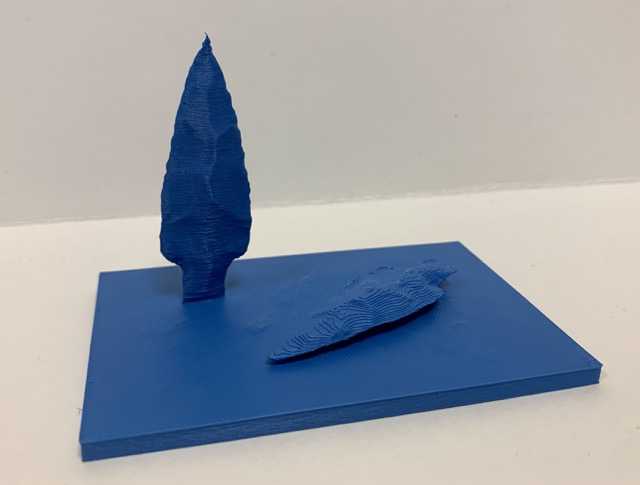 a 3D printed object made of a short rectangular base with two arrowheads that appear to be hand made from obsidian.