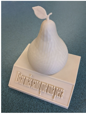 a 3D printed object with a base with text across the front which reads "“Estar más sano que una pera”. There is a 3D pear on top of the base.
