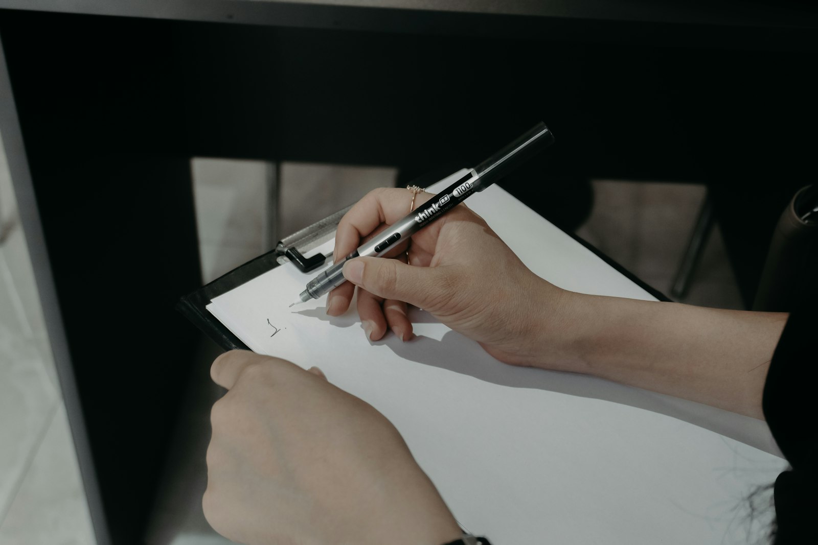 Mains remplissant un formulaire papier sur un support à pince