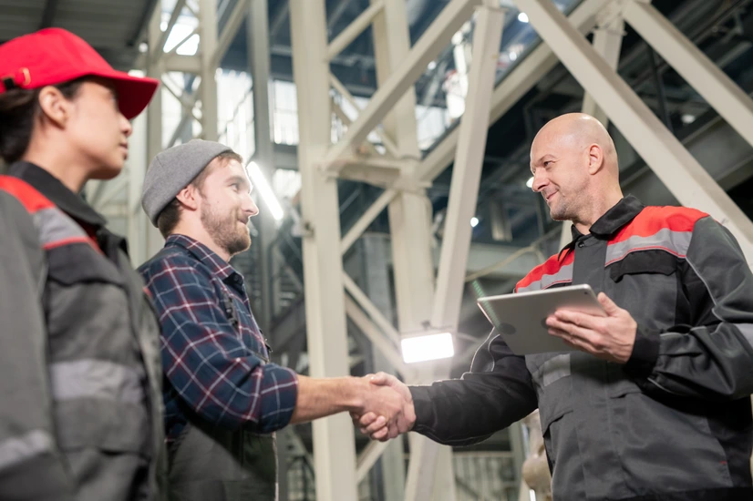 Scene showing a manufacturing worker receiving recognition from a team leader in front of peers