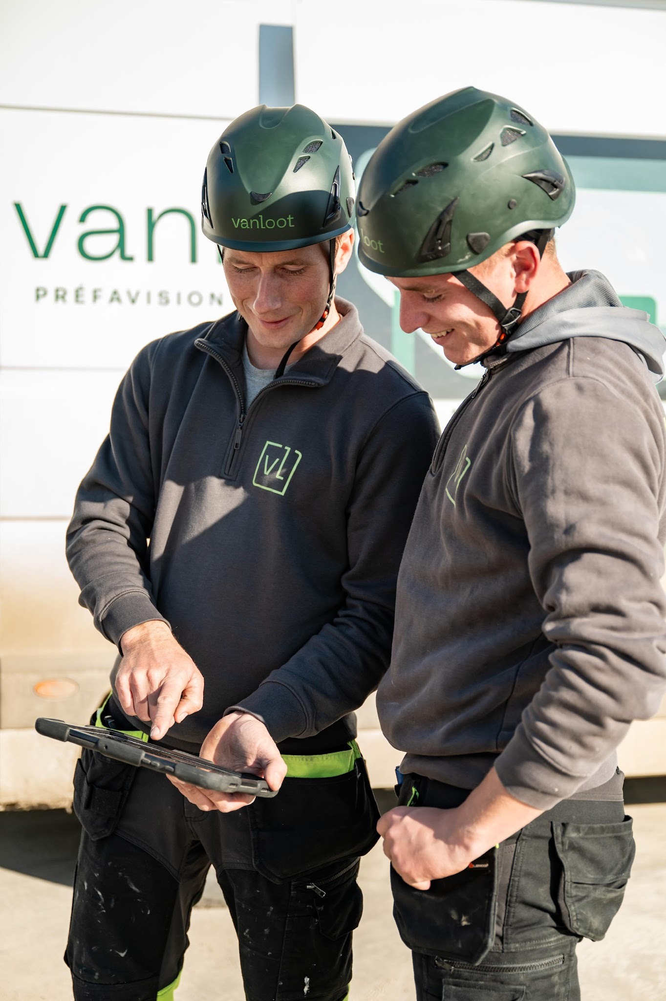 Vanloot medewerkers actief op een werf, met helm en informatie aan het bekijken