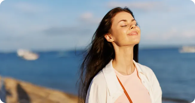 Company Formation In Dubai: Peaceful woman enjoying seaside with serene expression