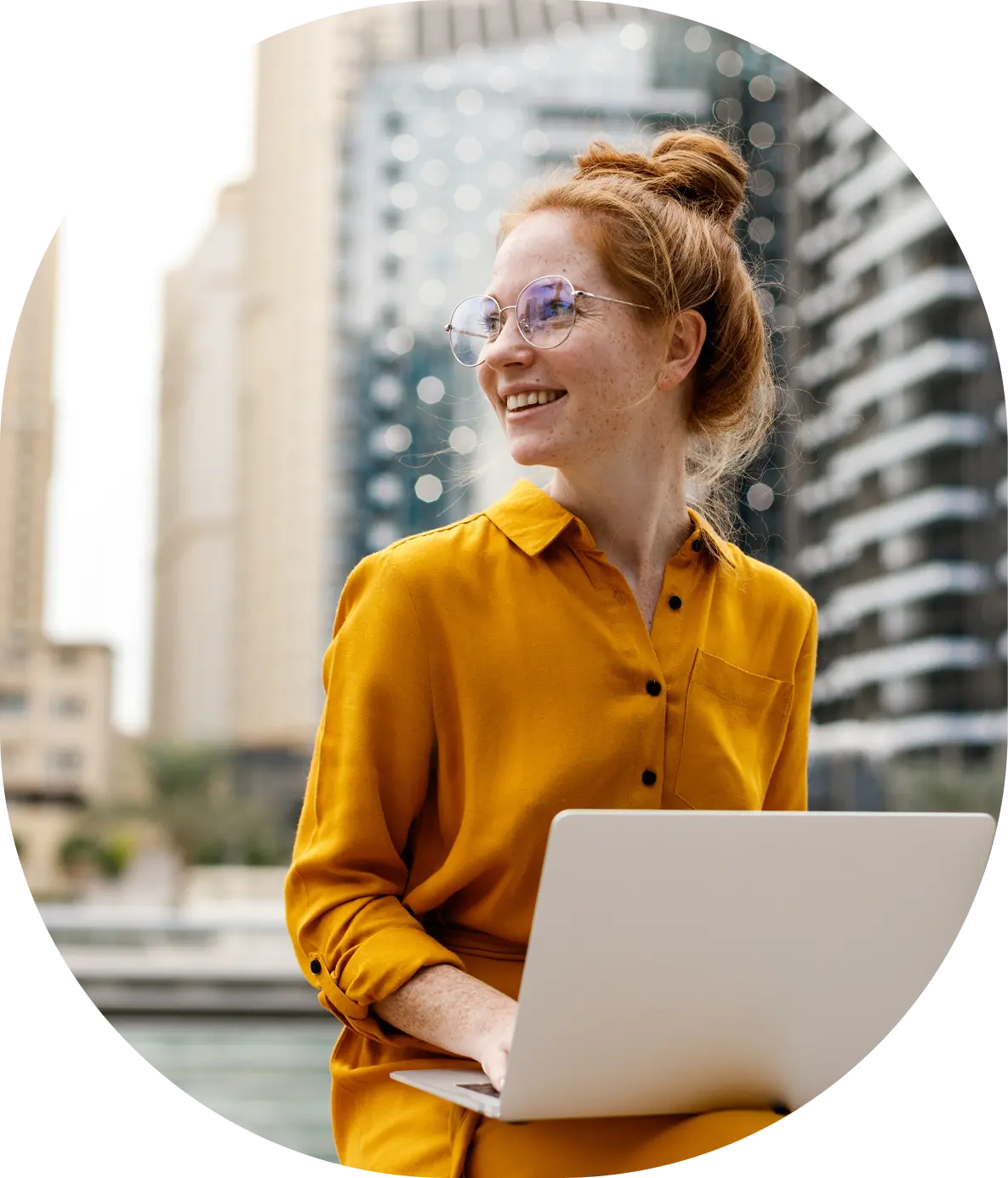 Free Zone In Dubai: Smiling professional working on laptop with city backdrop