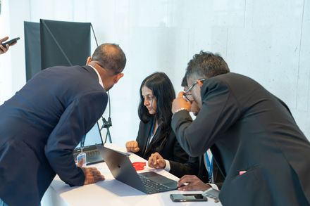 Team members huddled around a laptop, reviewing conference platform data.