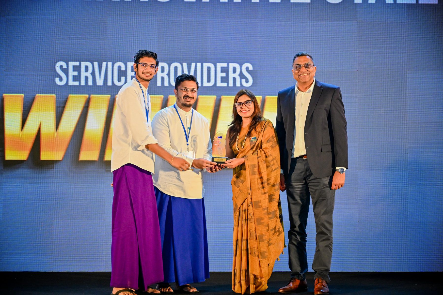 The team in sarongs and national shirts on stage receiving the Most Innovative Stall award
