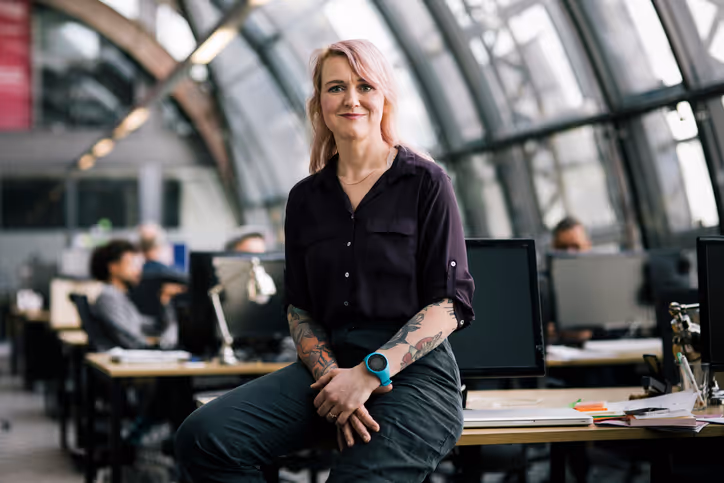 A female security professional leaning on a computer desk at the office.