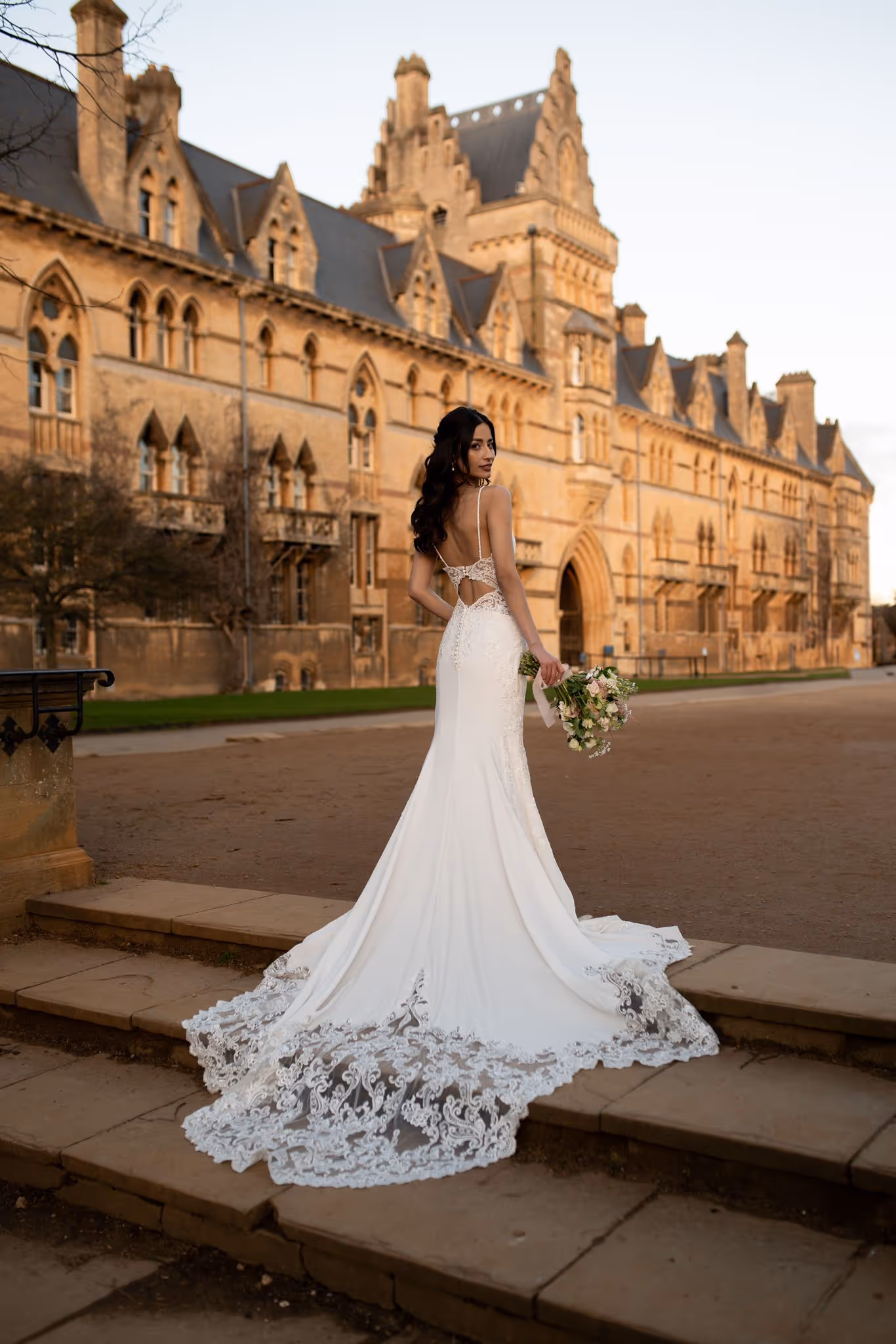 Bride in wedding dress stood on top of stairs in Oxford