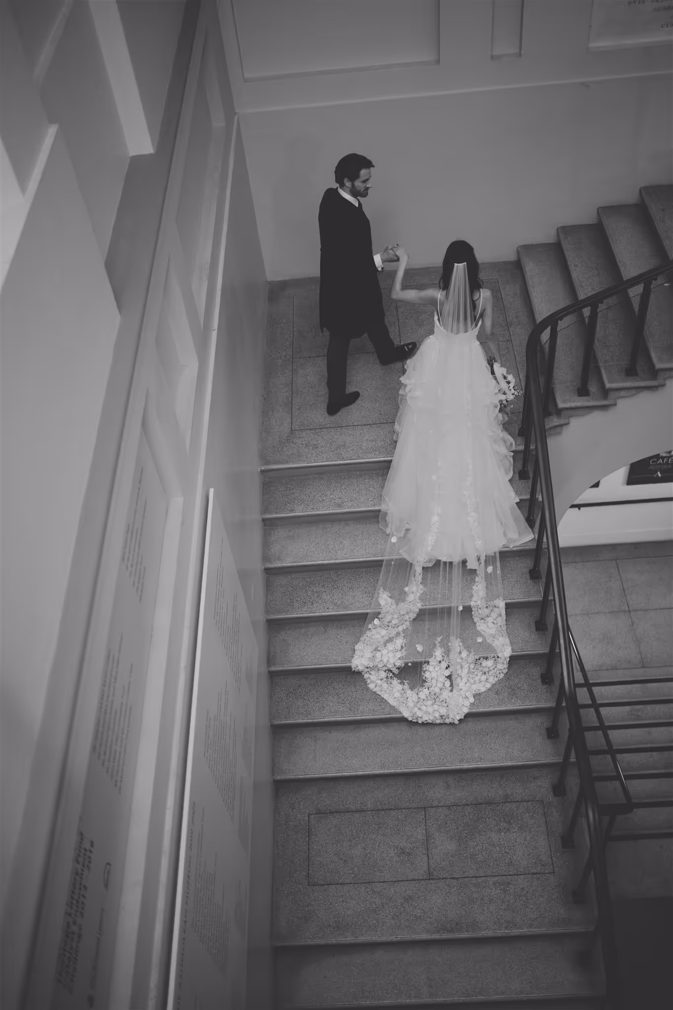 Bride in wedding dress and veil and groom walking up stairs