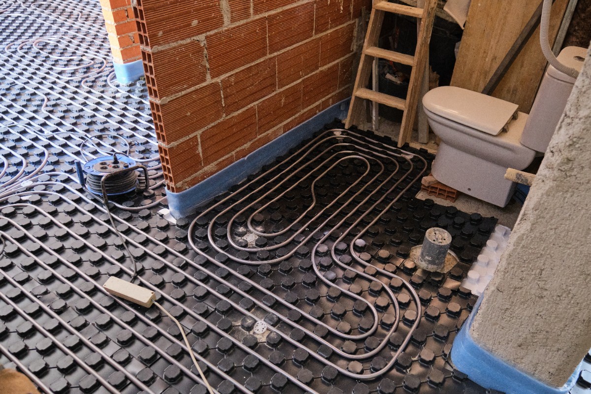 Hydronic radiant floor heating pipes installed over insulation panels prior to tile placement.