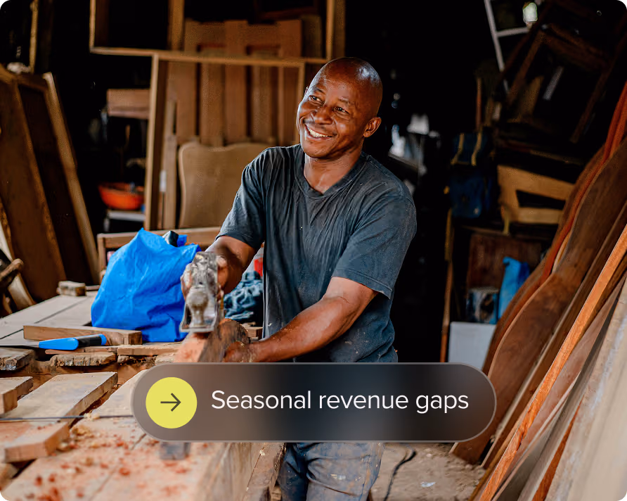 Smiling man working with woodworking tools in a workshop with wooden planks.
