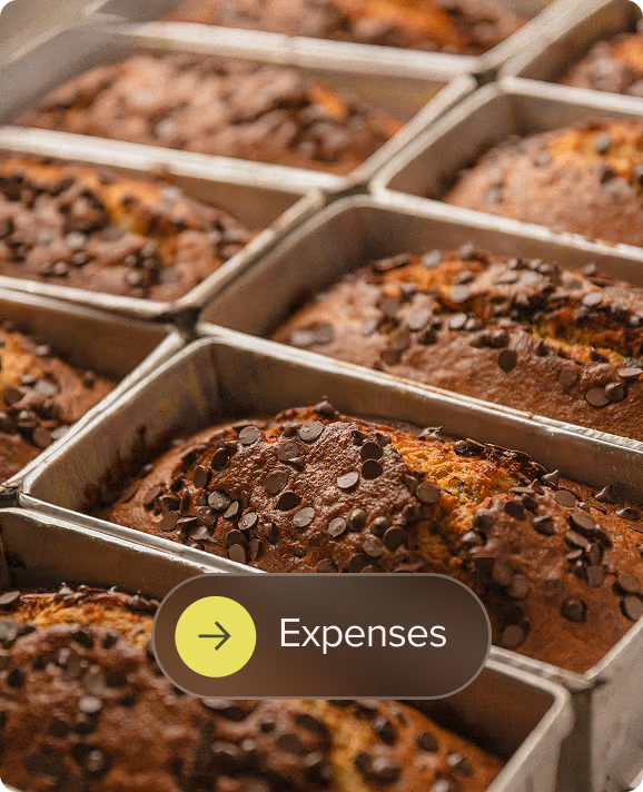 Rows of freshly baked chocolate chip banana bread loaves in baking pans.