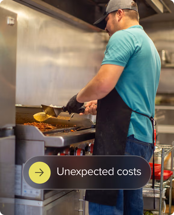 Cook wearing a cap and apron prepares food on a grill in a commercial kitchen.