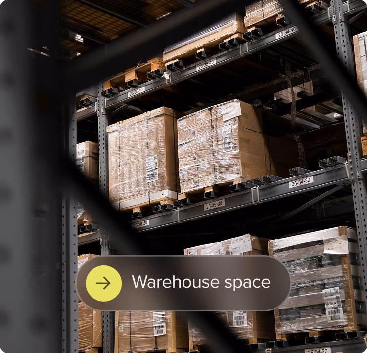 Stacks of shrink-wrapped pallets stored on metal shelves in a warehouse space.