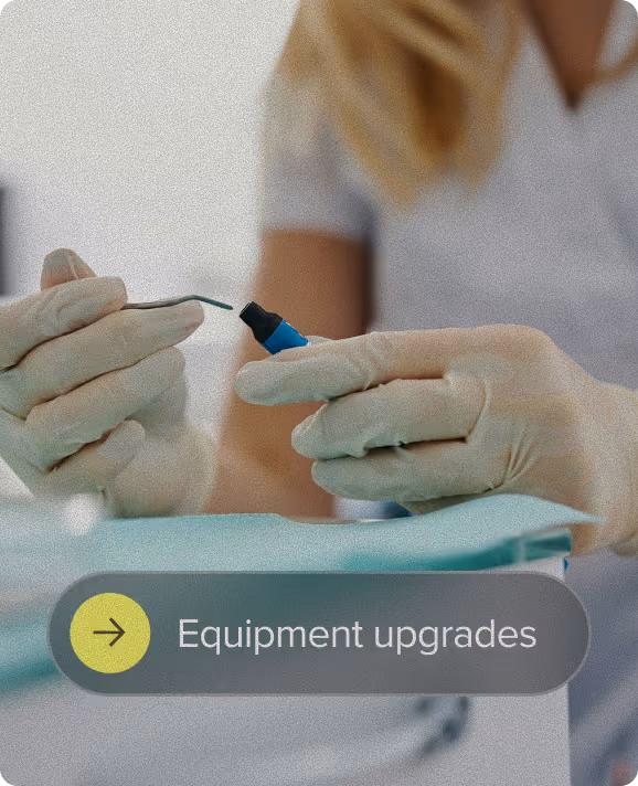 Close-up of gloved hands holding a dental instrument, with a blurred person in a white uniform in the background and a text overlay that reads 'Equipment upgrades.'