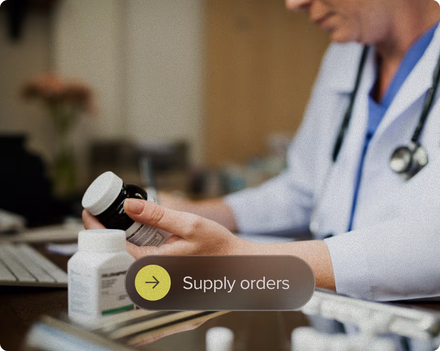 A healthcare professional in a white coat with a stethoscope holds a pill bottle, with another bottle on the desk, near a keyboard, overlaid with a button labeled 'Supply orders'.