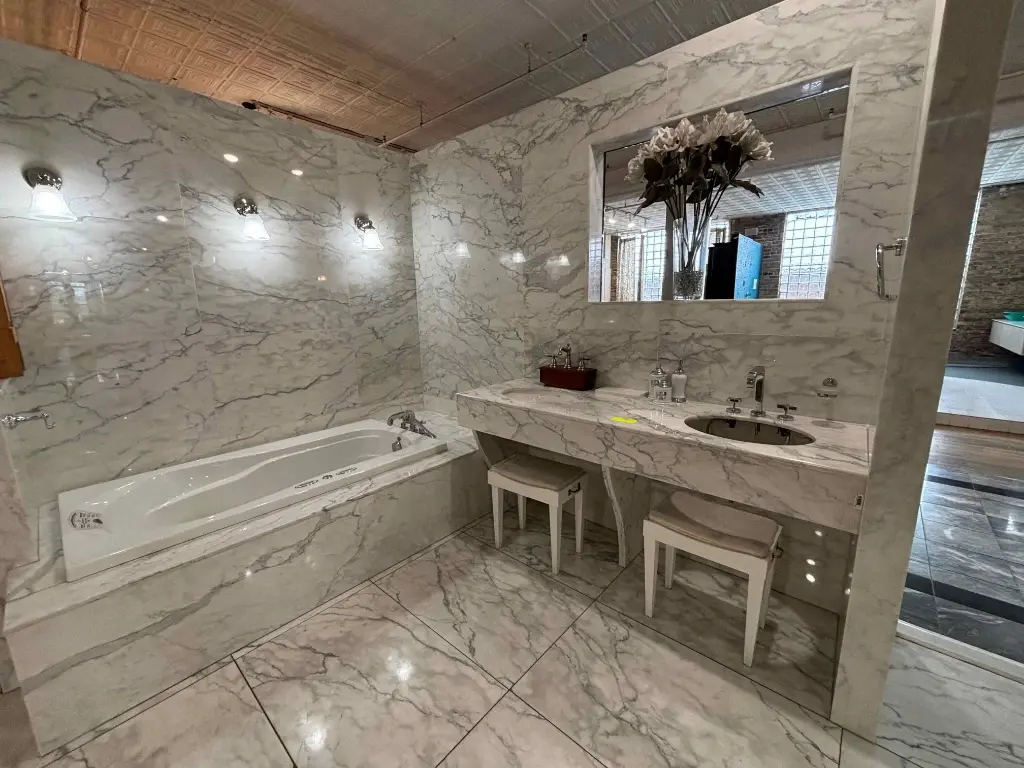 Marble-clad bathroom showroom display with tub and vanity – Stone City Auction