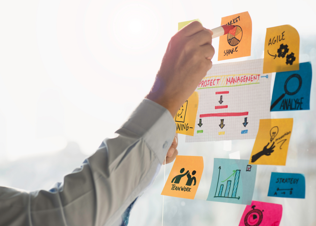 Hand placing sticky notes on agile project board