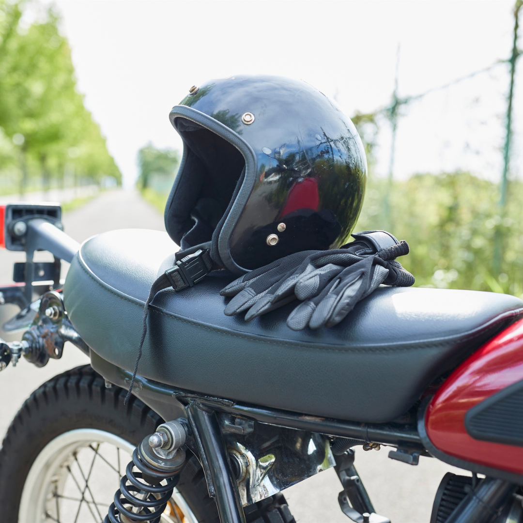 A motorcycle helmet and riding gloves resting on the seat of a motorcycle