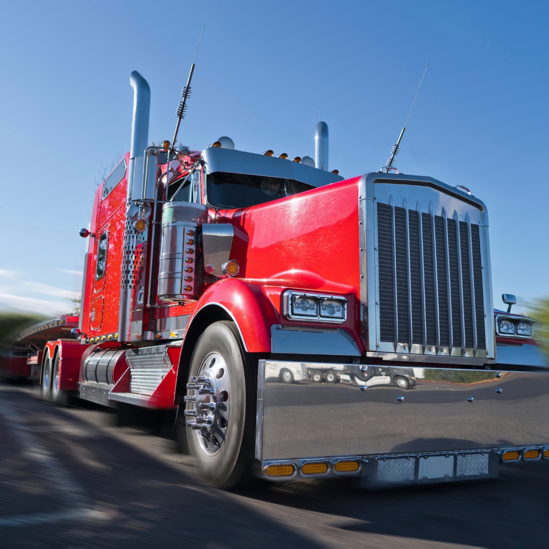 A red semi truck hauling a trailer on a highway