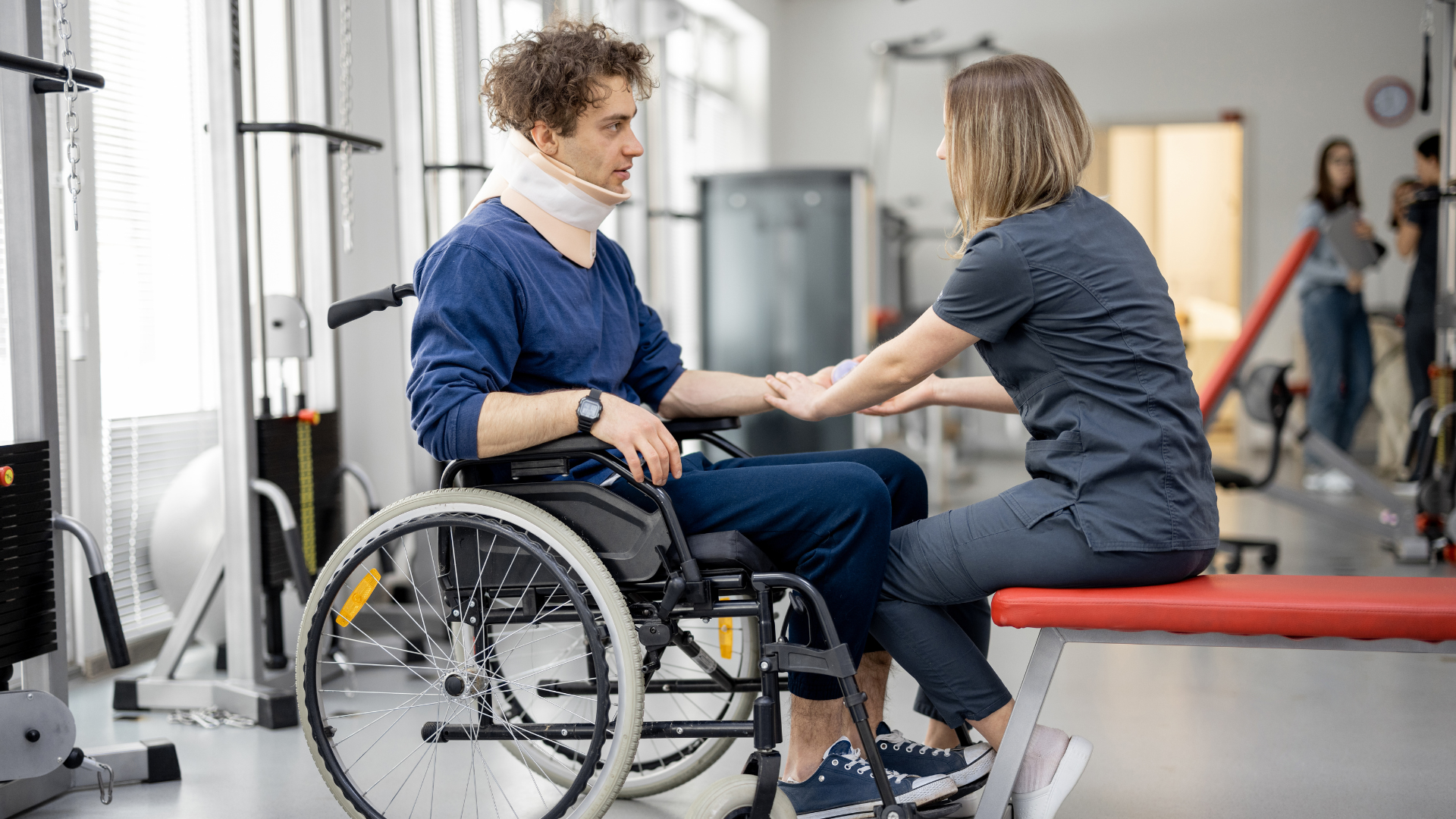 A man with a neck injury in a wheelchair working with a physical therapist