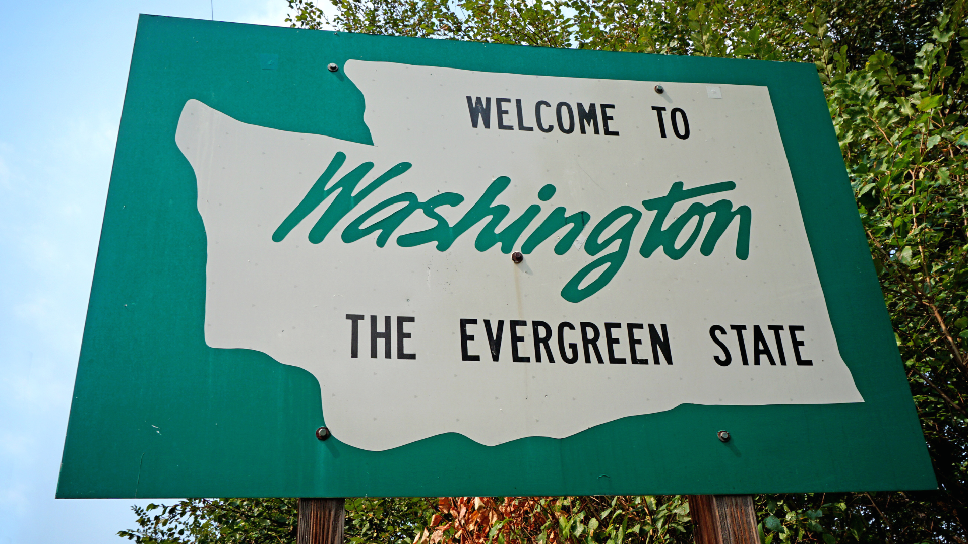 A picture of a "Welcome To Washington" sign with trees in the background