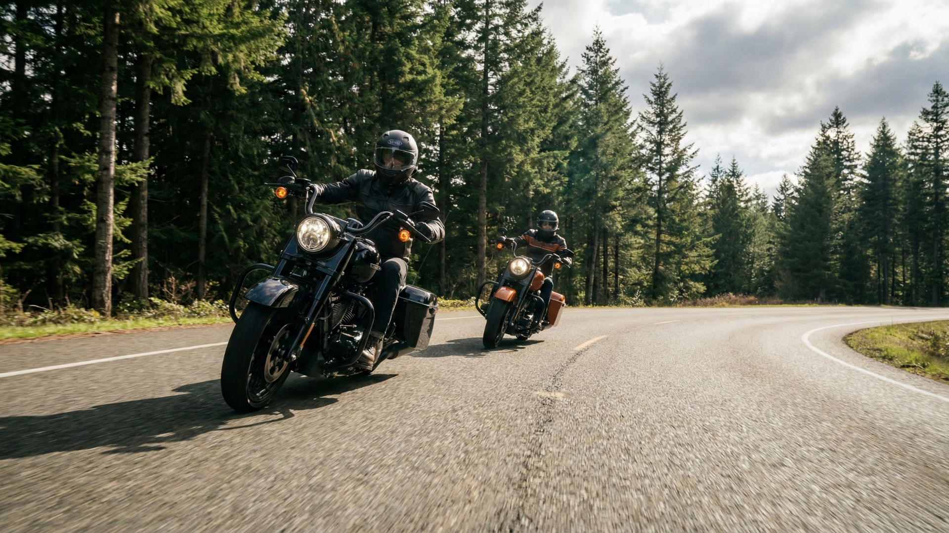 Two motorcycle riders riding on a highway through a forest