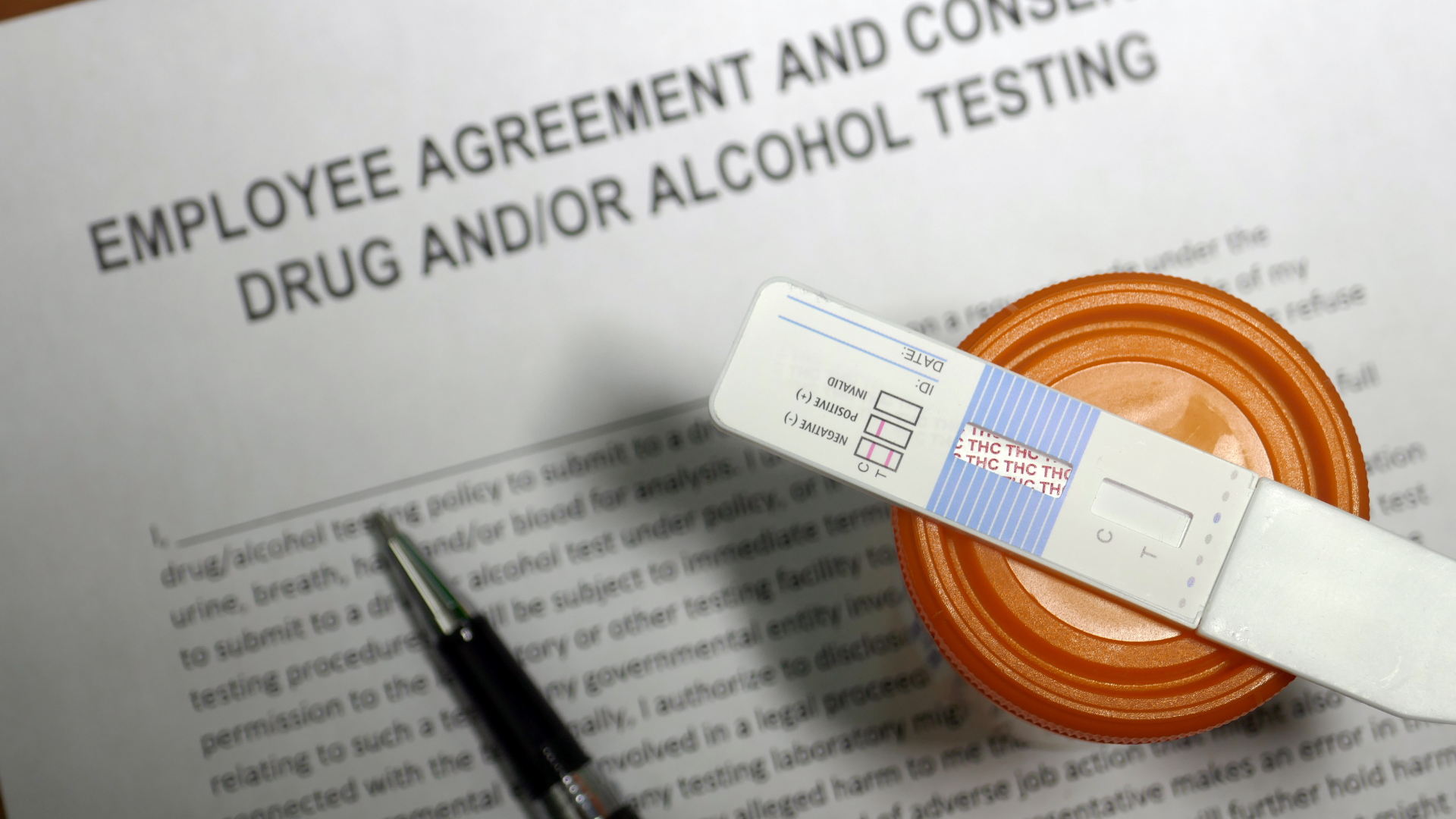 A picture of a drug test strip and an employee contract for drug testing