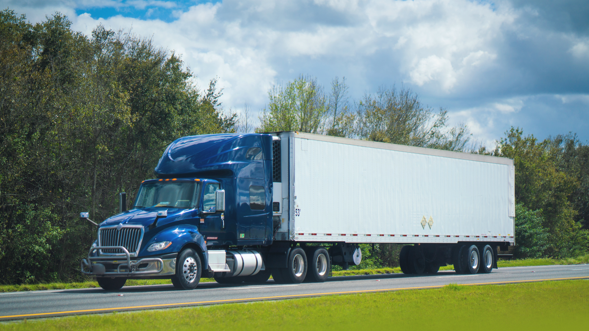 A blue semi truck hauling a white trailer on a highway