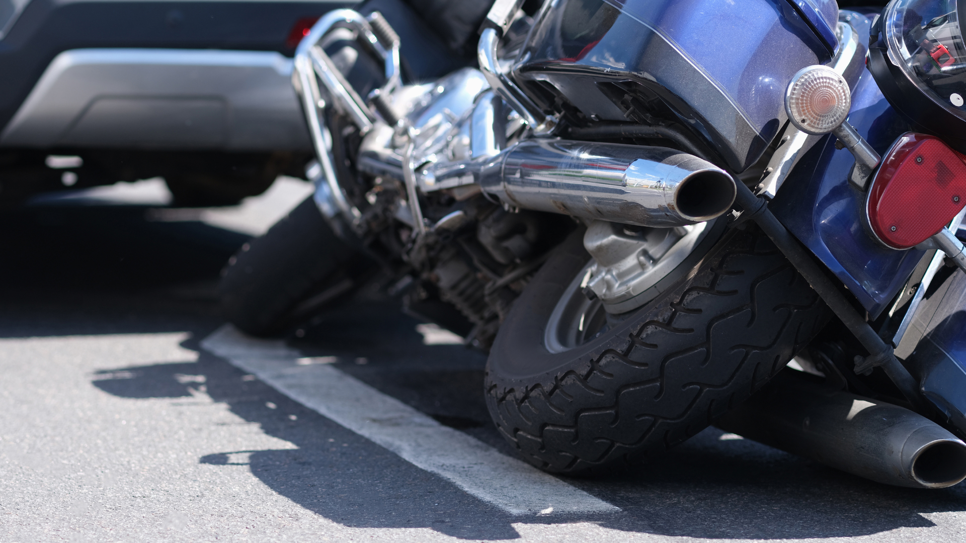 A motorcycle that is resting on it's side on the ground behind a car