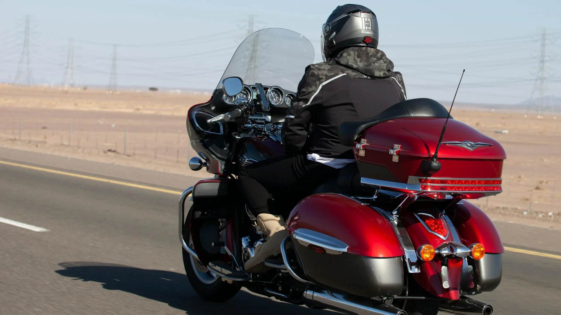 A motorcyclist riding a burnt orange touring style motorcycle on a highway