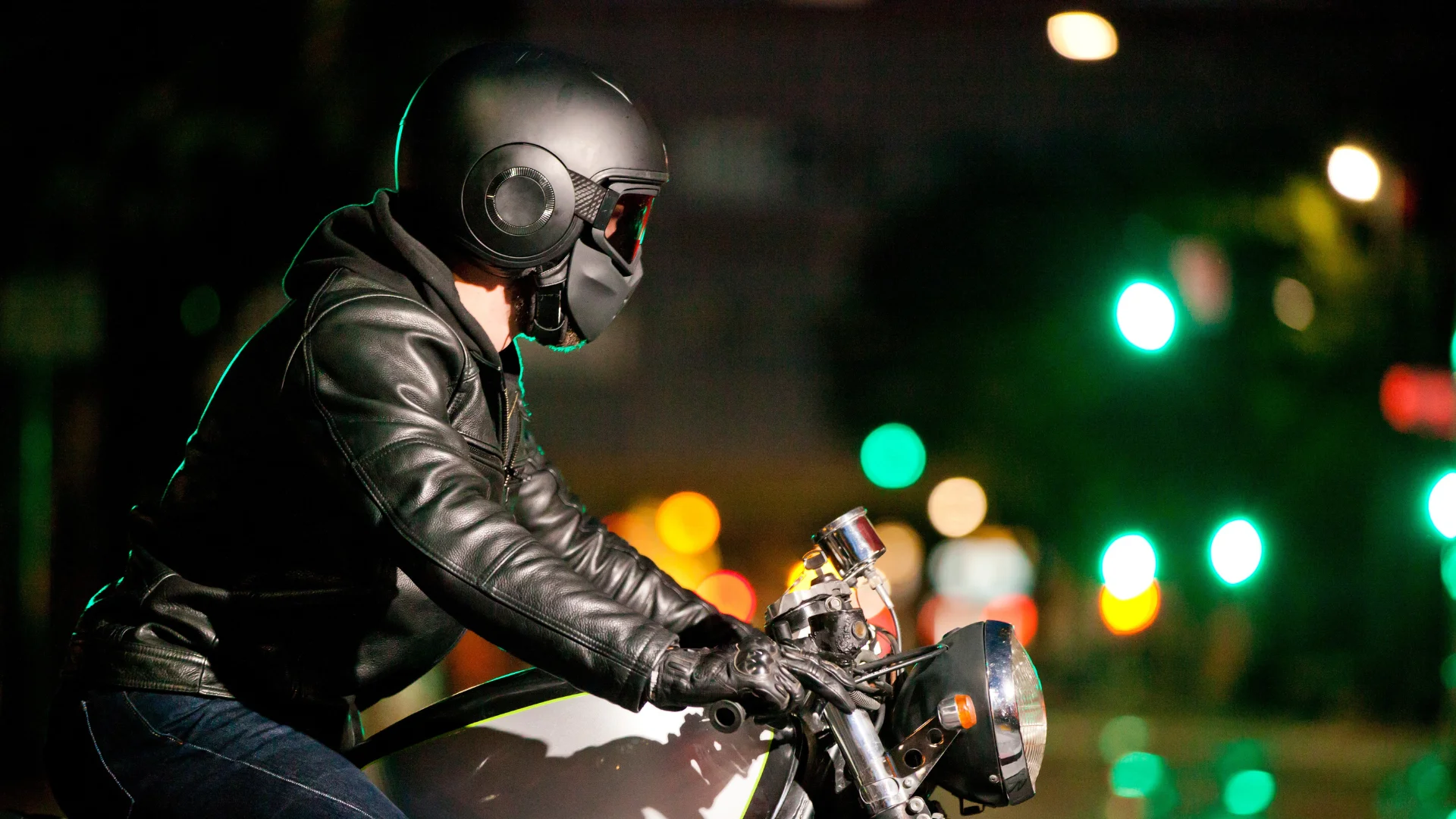 A motorcyclist at a stop at a city intersection at night