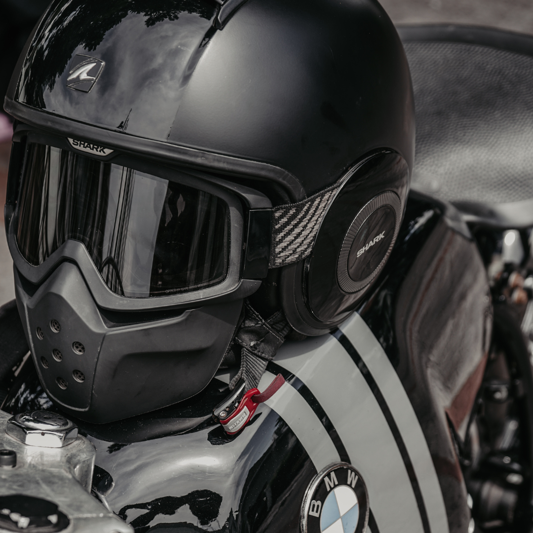 A black motorcycle helmet and goggles resting on a BMW motorcycle