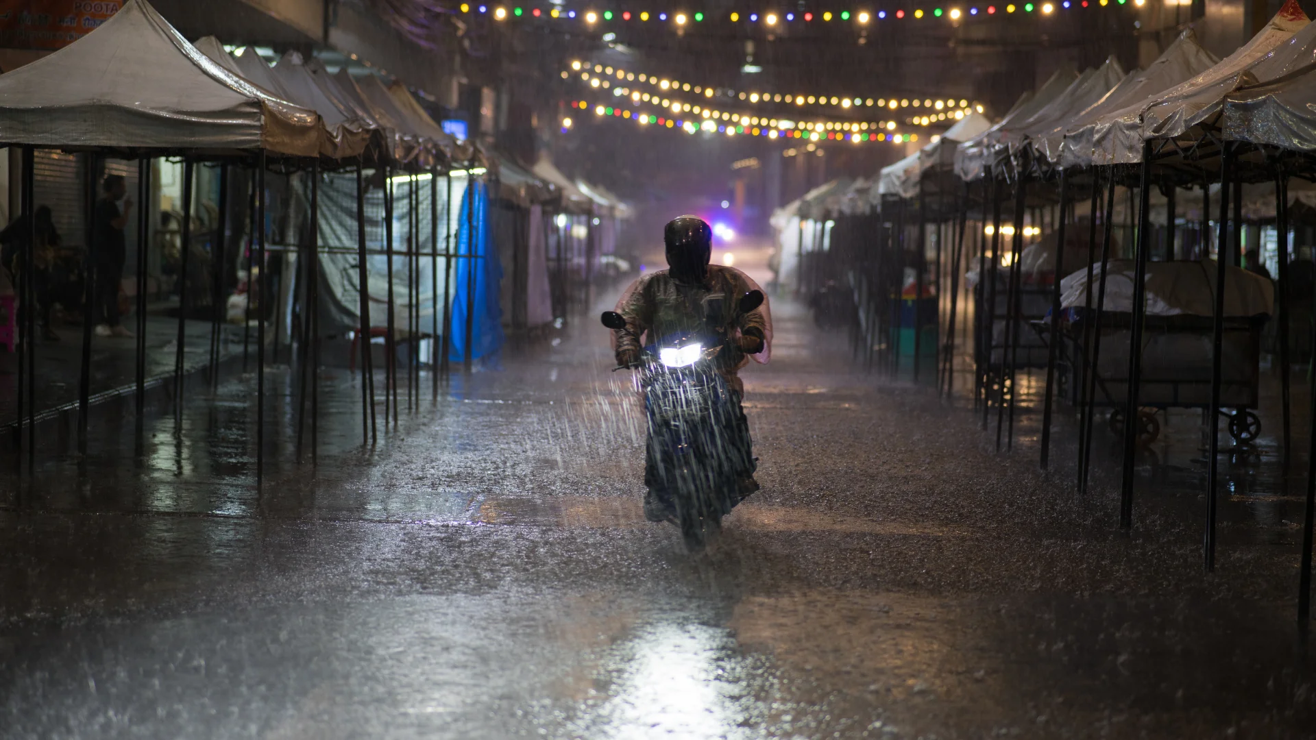 A motorcyclist riding in the rain at night on a city street
