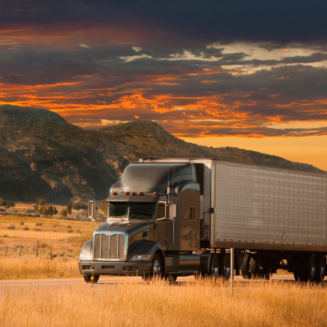 A semi truck hauling a trainer near Cheyenne, WY at sunset