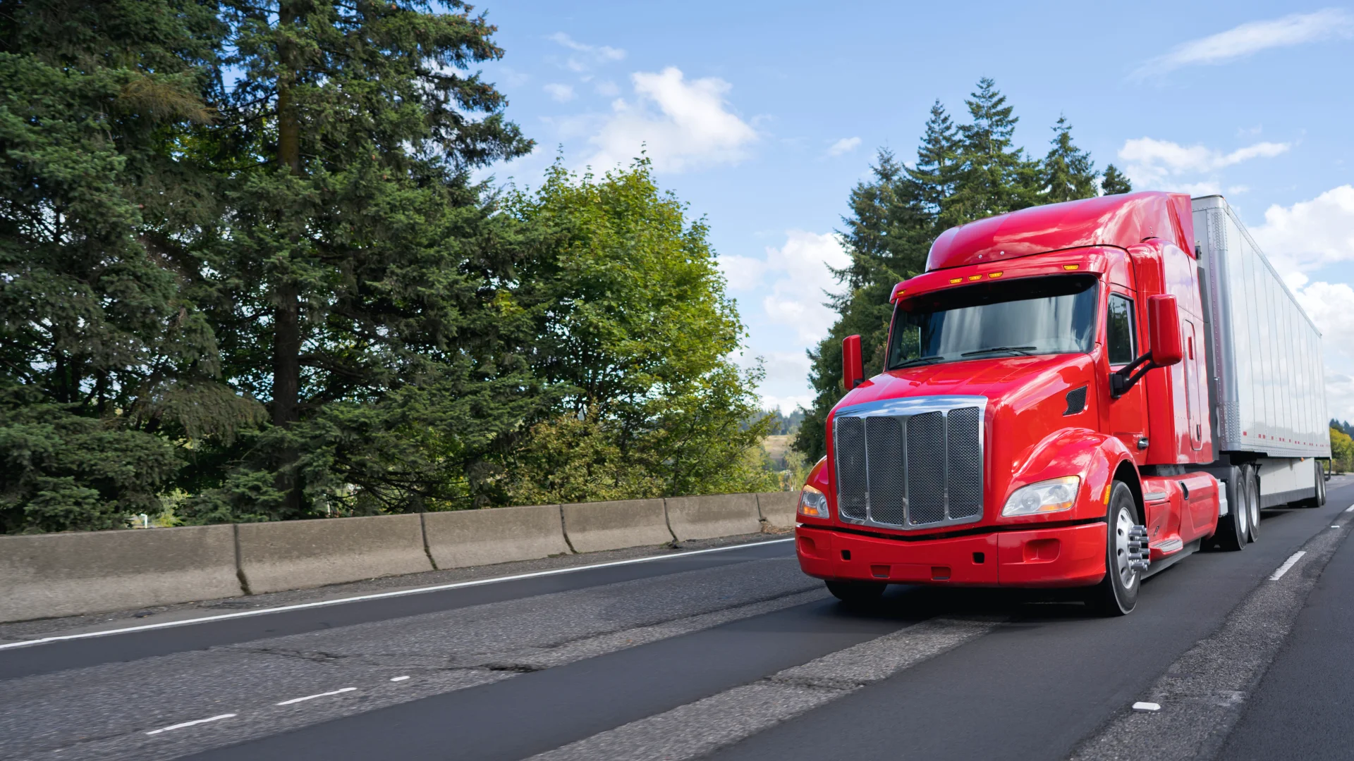 A red semi truck hauling a white trailer on a rural highway