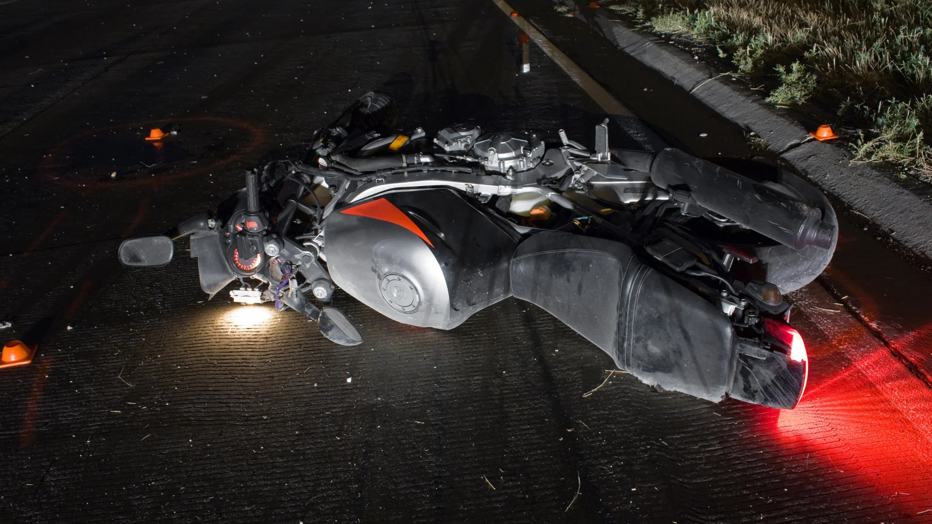 A black motorcycle laying on the ground after its been in an accident at night