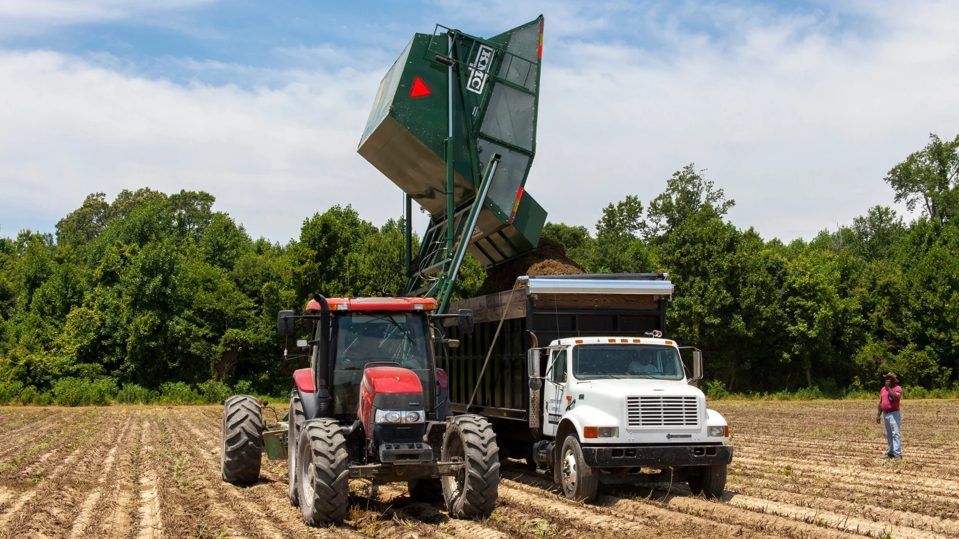 A tractor unloading into an agricultural truck in a field