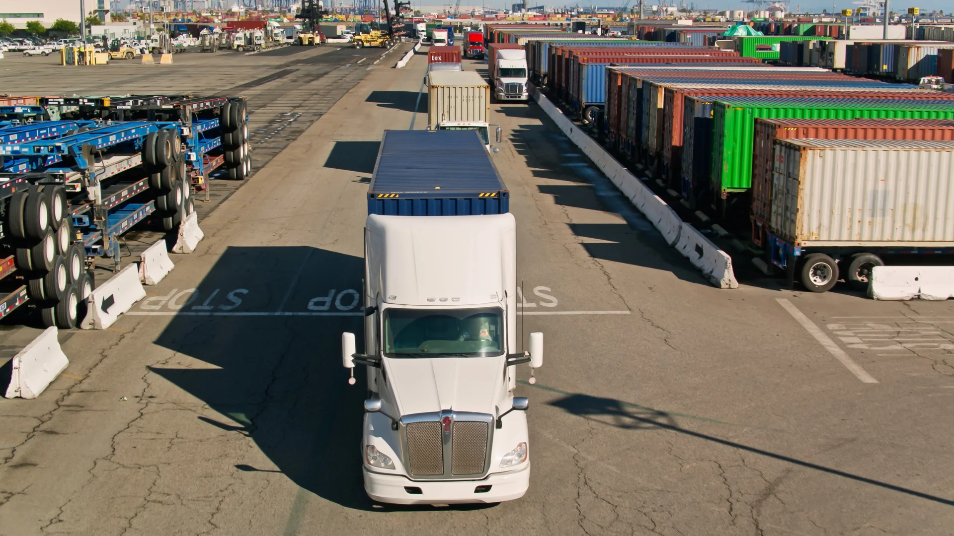 A white semi truck driving in a port yard