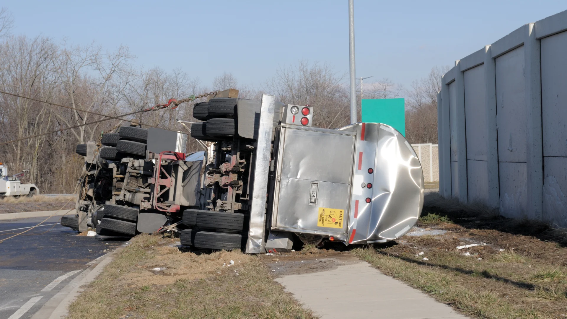 A tanker truck resting on its side on the ground after being in an accident