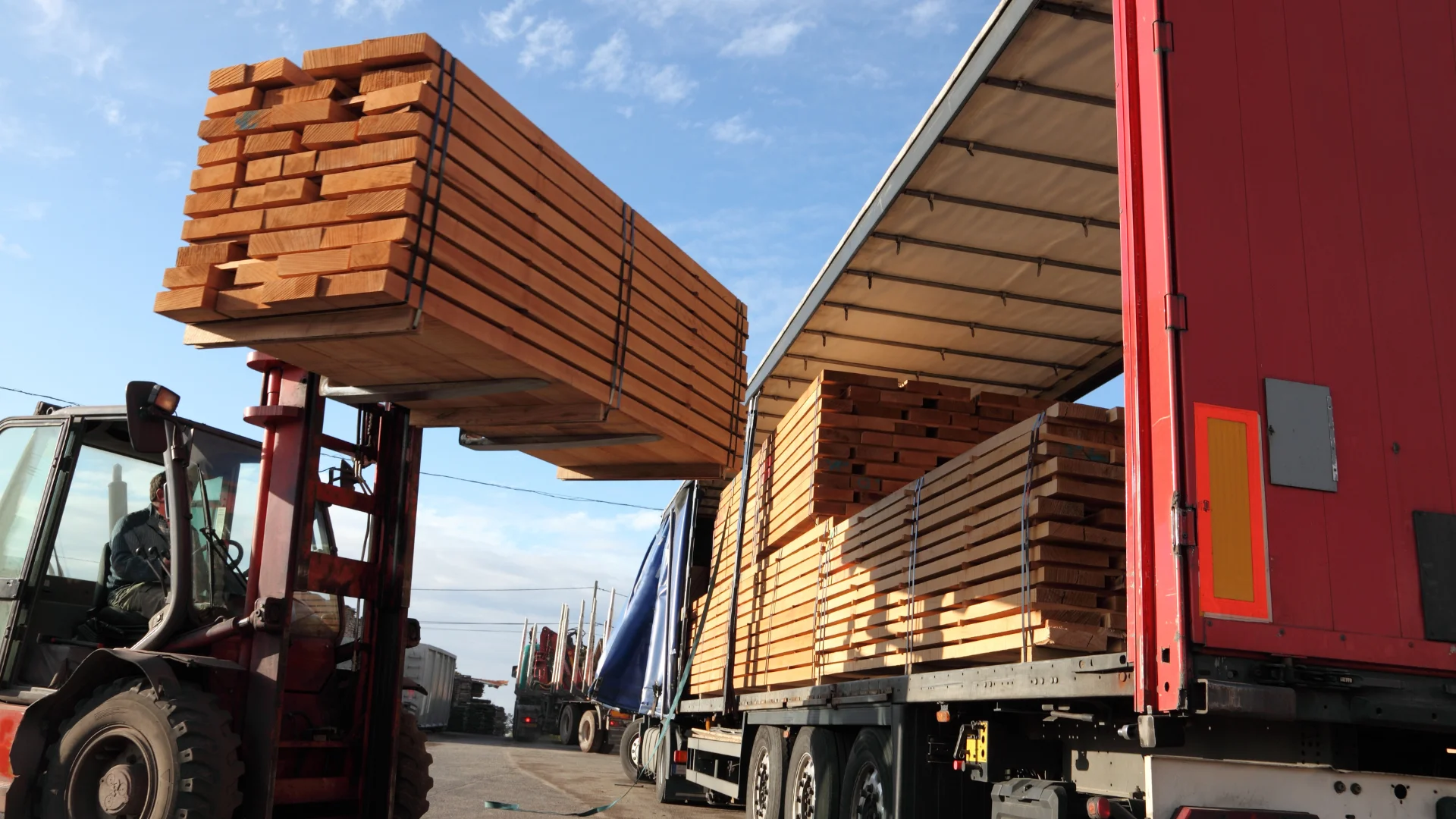 A forklift loading a semi truck trailer with wood