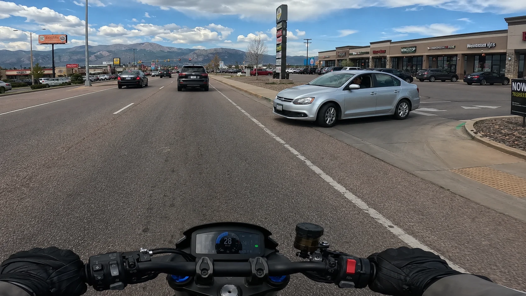 Car pulling out of a parking lot in front of a motorcycle in Colorado Springs