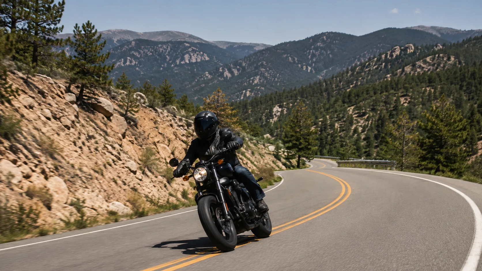 Motorcyclist in protective gear riding through a winding Colorado mountain and foothill road
